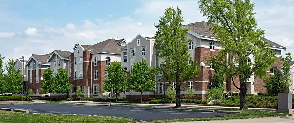 An apartment complex parking lot with surrounding landscaping.