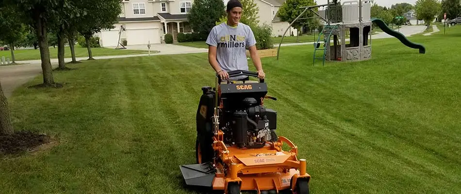 Spider Lawn & Landscape team member mowing a home lawn in Noblesville, IN.